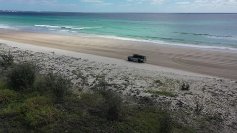 Die-Luftaufnahme-Umkreist-Langsam-Einen-LKW,-Der-Am-Weitläufigen-Australischen-Sandstrand-Fährt