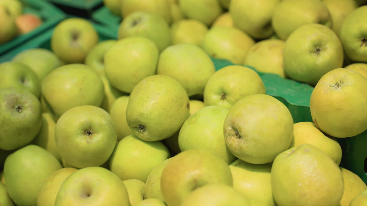 식료품 가게의 상자에서 두 개의 사과를 집어 들고 있는 손의 손바닥 팔를 착용한 모습. 휴대용 카메라로 찍은 사진