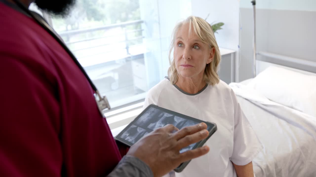African american male doctor with digital tablet talking to caucasian female patient at hospital