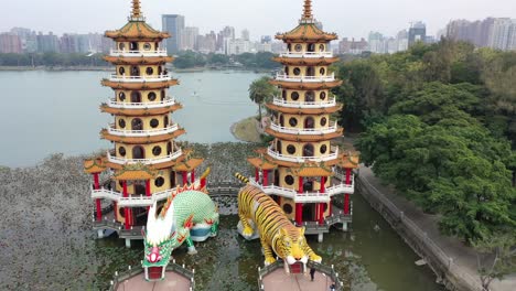 Vista-Frontal-De-Movimiento-Circular-En-El-Sentido-De-Las-Agujas-Del-Reloj-Del-Espectacular-Templo-De-Pagodas-De-Dragón-Y-Tigre-Con-Torre-De-Siete-Pisos-Ubicada-En-El-Lago-De-Loto-En-Kaohsiung-Taiwán-Con-Actividades-Acuáticas-En-El-Fondo