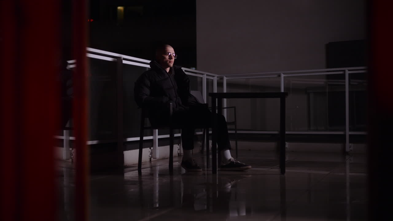 Uomo seduto su un balcone di notte