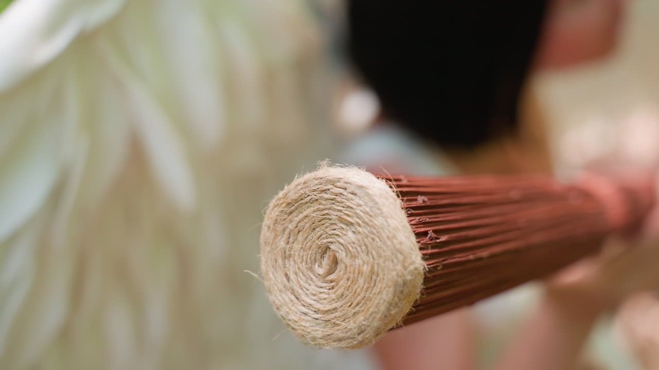 Extreme close up of fairy creature holding and rotating wooden staff wrapped with rope under soft forest light, focusing on spiral texture and movement, symbolizing connection