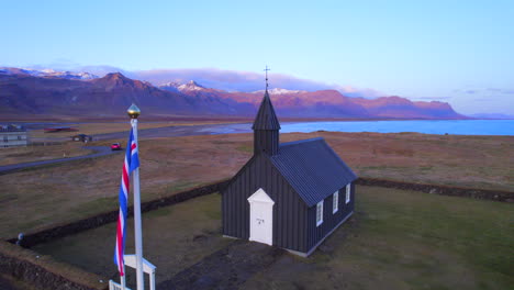 B&uacute;&eth;akirkja black church and Iceland&acute;s flag under sunset sky
