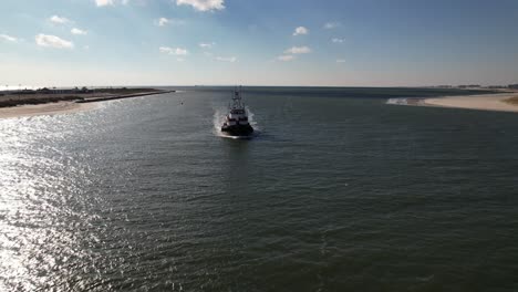 an aerial view of a tugboat on a sunny day in the east rockaway inlet in queens, ny