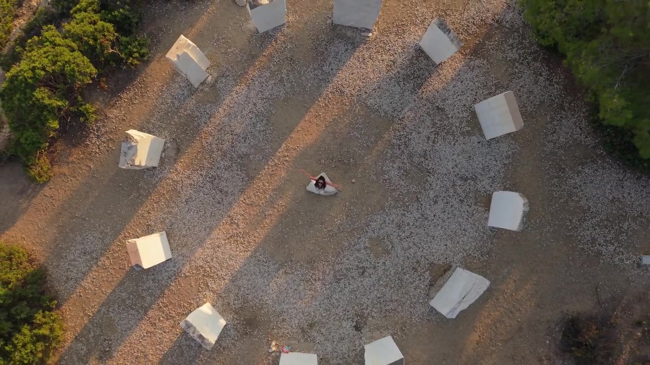 Ripresa verticale con drone di una donna che volteggia al centro della Corona di Limenaria a Thassos, evidenziando simmetria e movimento.