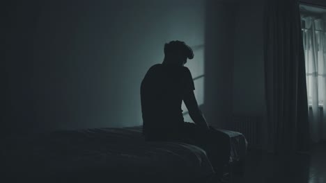 young man sitting on bed's edge, drowning in deep emotional shadows, silently wrestling with inner turmoil and unspoken psychological struggles during quiet nighttime moments