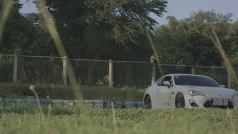white race car drifting and driving around a motor sports track