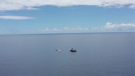 Wide panning aerial shot of a ferry approaching a submarine in the open ocean off the shores of Kailua-Kona on the island of Hawai&#039;i