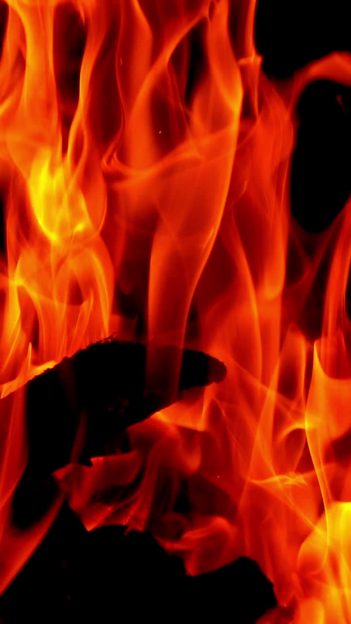 Burning fire. Bright burning wood slow motion. Splashes of flame and live coals. Vertical video