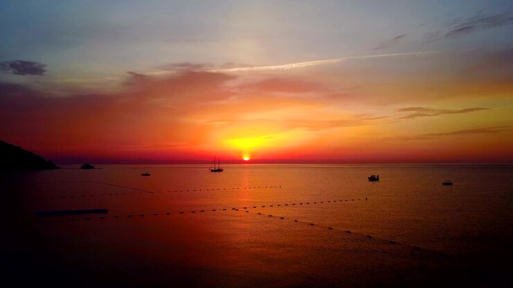 Aerial Drone Flight In To Sunrise over the calm Sea