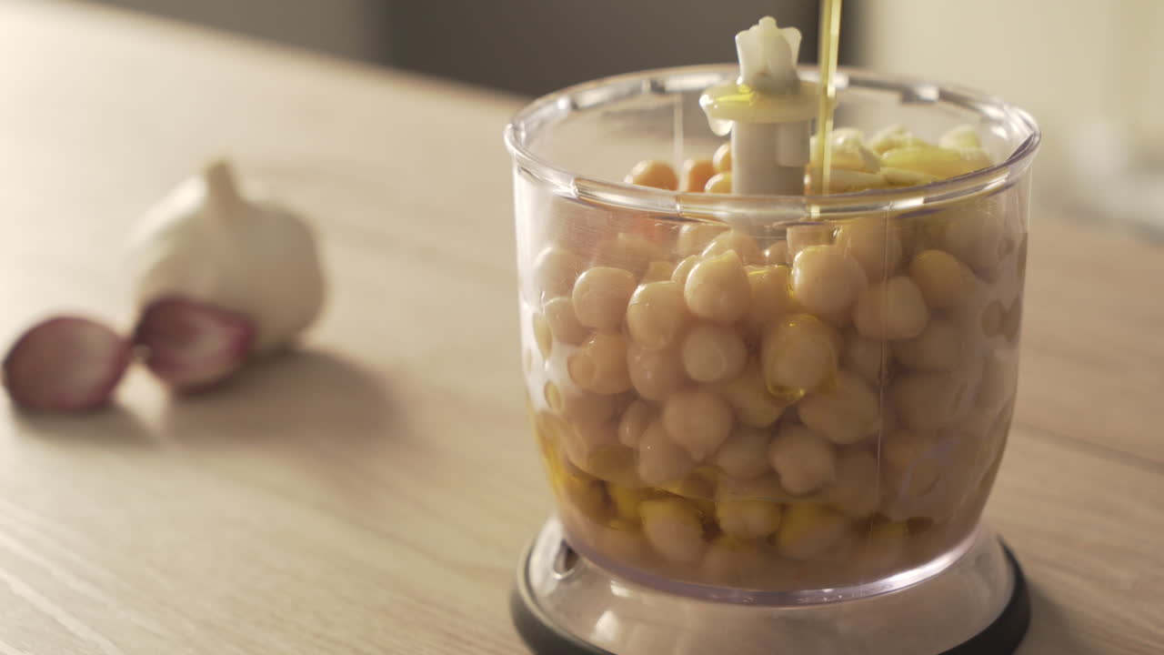 Preparing hummus with chickpeas and olive oil in a blender