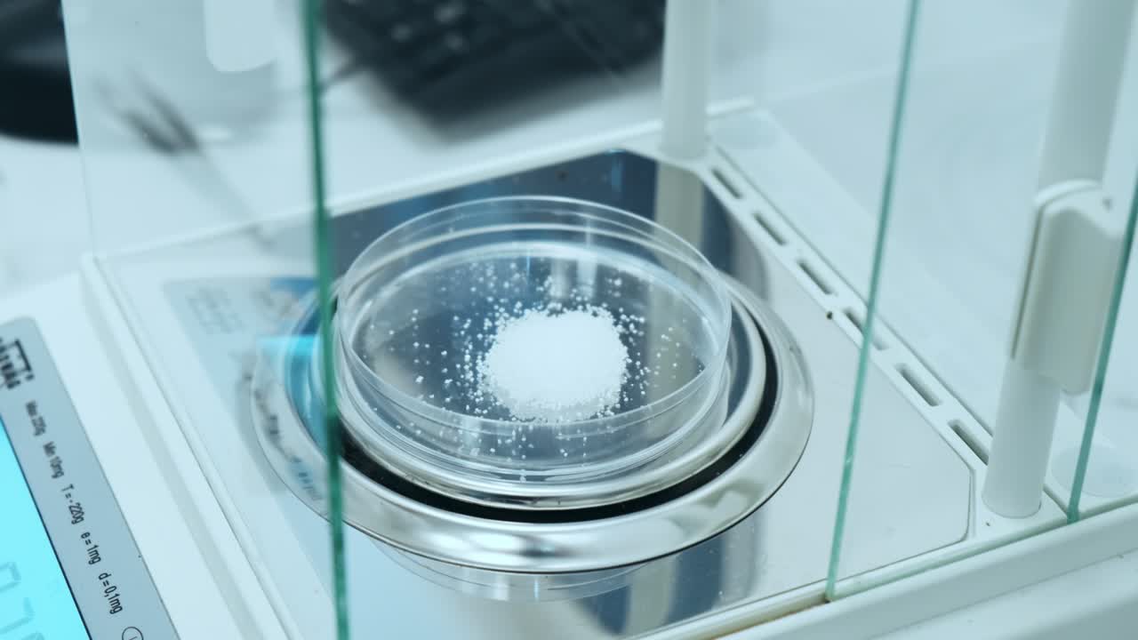 Scientist or chemist weighs samples or white powder using digital analytical scales or balances. Preparation of standard solution for pharmaceutical or clinical analysis