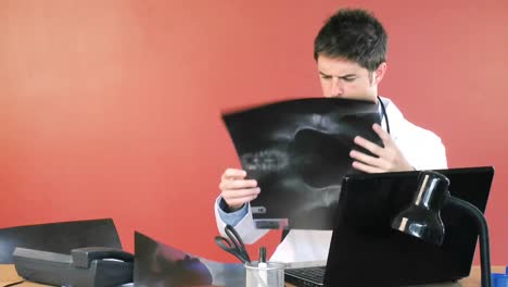 médico masculino usando una computadora portátil y estudiando un metraje de rayos x