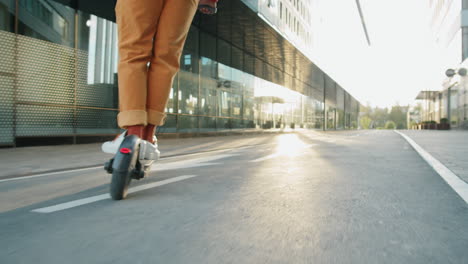 piernas de un hombre montando un scooter eléctrico en la ciudad