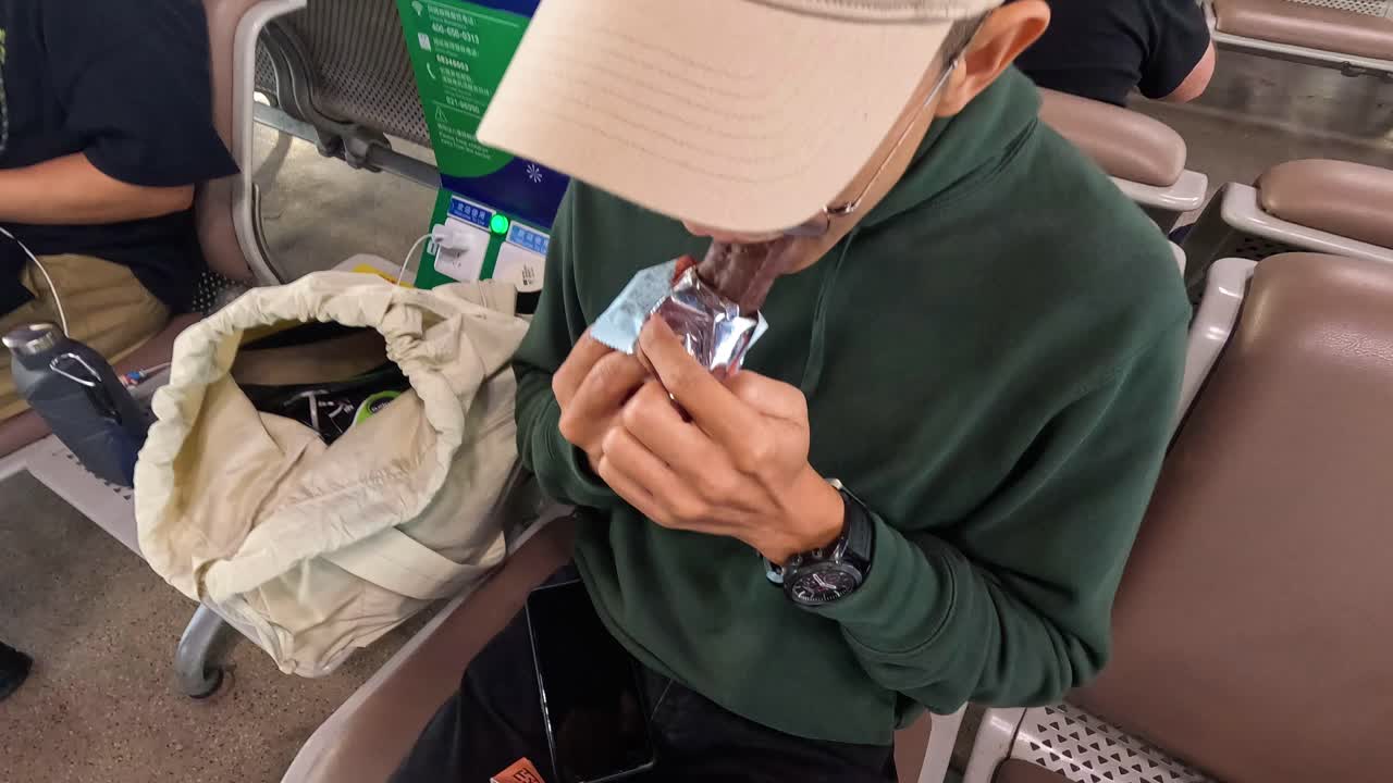 사람은 기다리는 동안 초콜릿을 풀고 먹습니다.