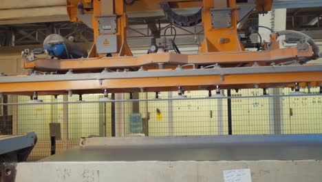 manipulator with vacuum cups puts metal sheet on production line with conveyor in plant workshop