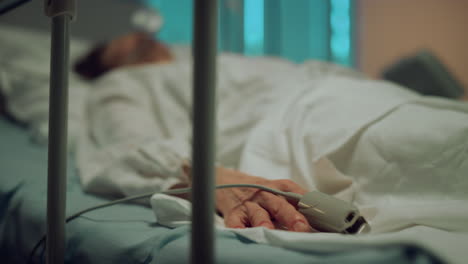 patient hand moving finger in hospital bed closeup. sick person wake up in ward.