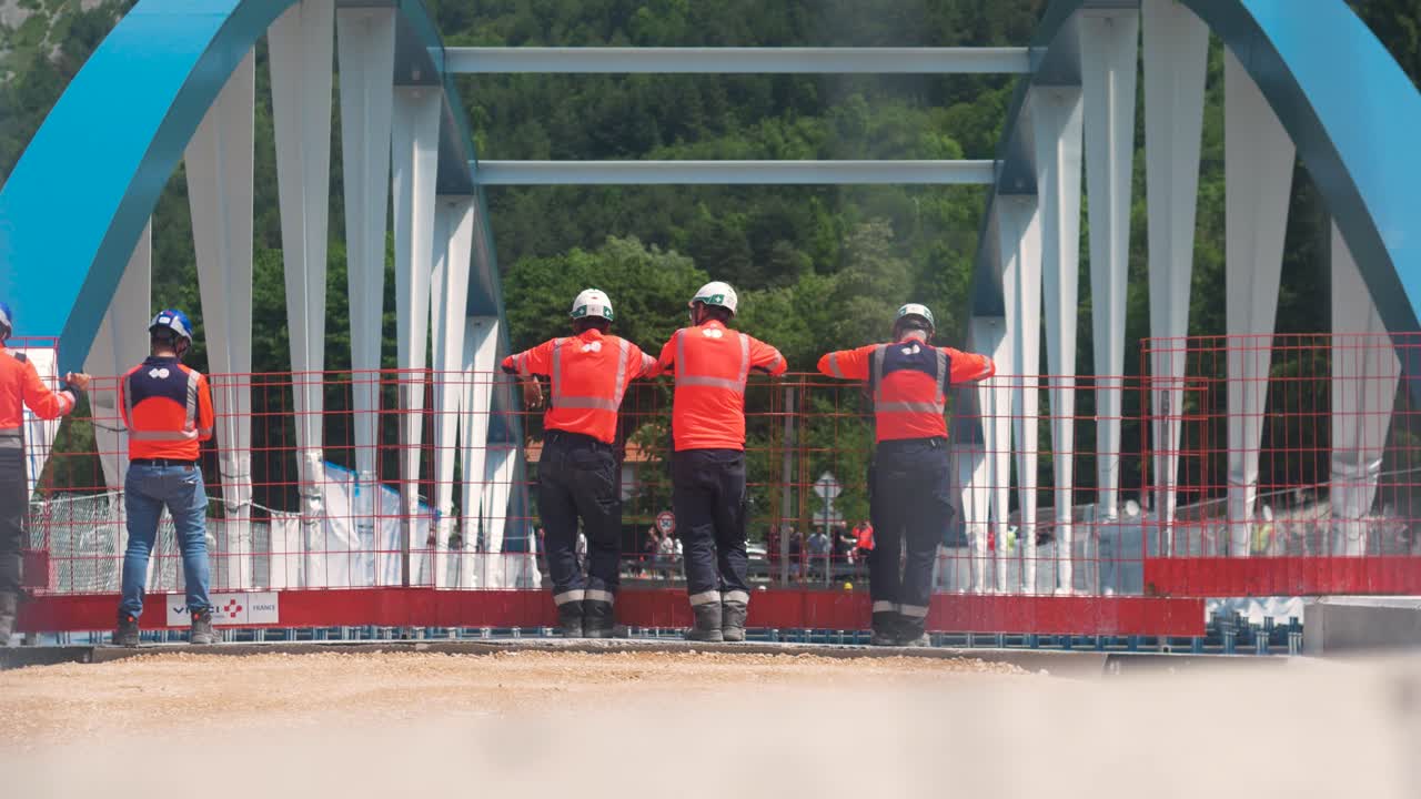 Workers securing bridge rigging on a construction site in Tende, South of France, wearing safety gear