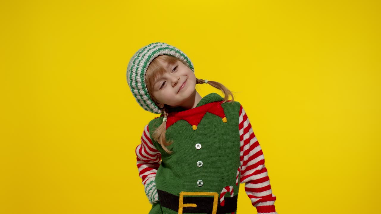 Dívka v kostýmu vánočního skřítka, pomocníka Santy, dostává dárkovou krabici. Novoroční svátek.