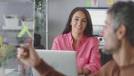 Businessman-In-Creative-Office-Writing-Ideas-On-Transparent-Screen-Talking-To-Female-Colleague