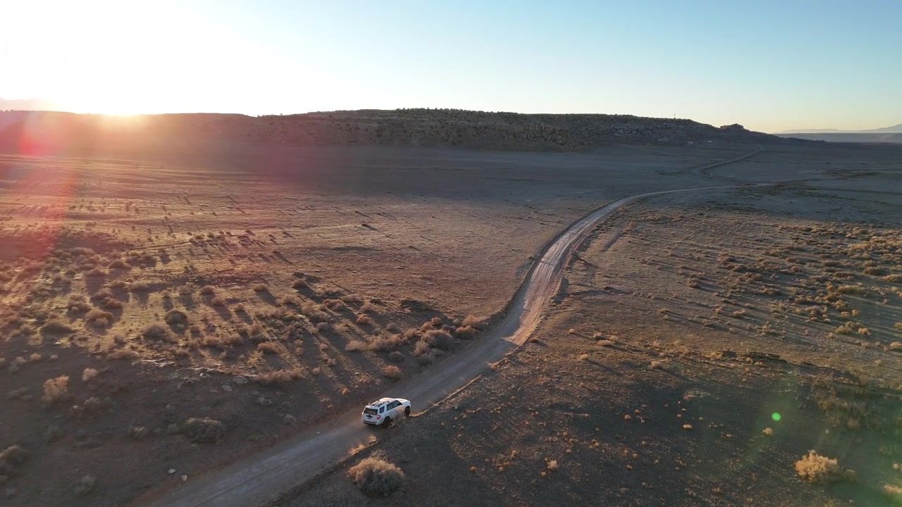 Ripresa con drone di un SUV bianco che si muove su una strada nel deserto nella natura selvaggia al confine tra gli stati di Utah e Colorado, USA