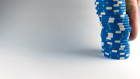 male finger pushing down a stack of blue poker chips, isolated, still, slomo