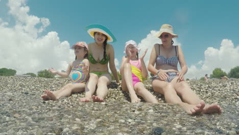 two young women in bikinis along with their daughters have fun on the seaside play with the waves la