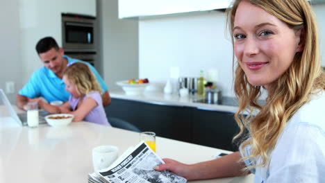 mother reading the paper while family has breakfast
