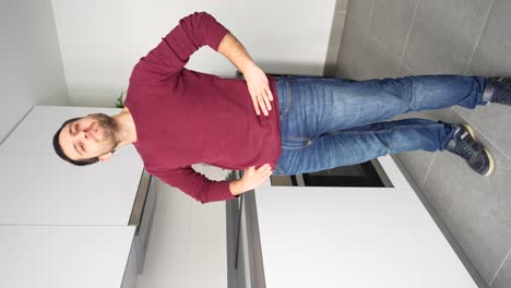 Man-in-red-shirt-and-jeans-holds-arms-on-waist-nodding-his-head-in-agreement