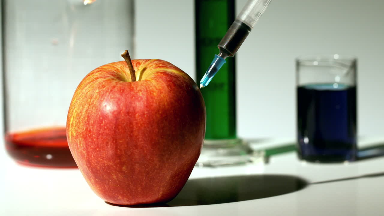 una jeringa que inyecta un producto químico en una manzana