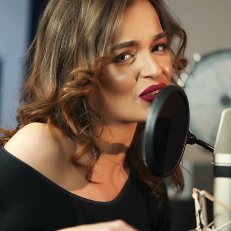 young female singer recording album in the professional studio. woman singing a song in music recording studio. square video