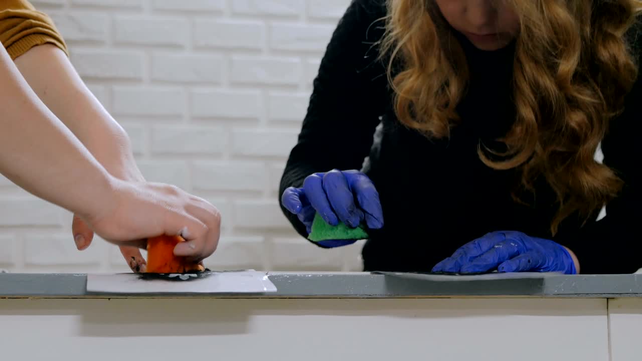 manos de mujeres pintando círculo de madera