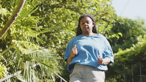 Vista-Frontal-De-Una-Mujer-Con-Cuerpo-Positivo-Corriendo-Escaleras-Arriba-En-El-Parque