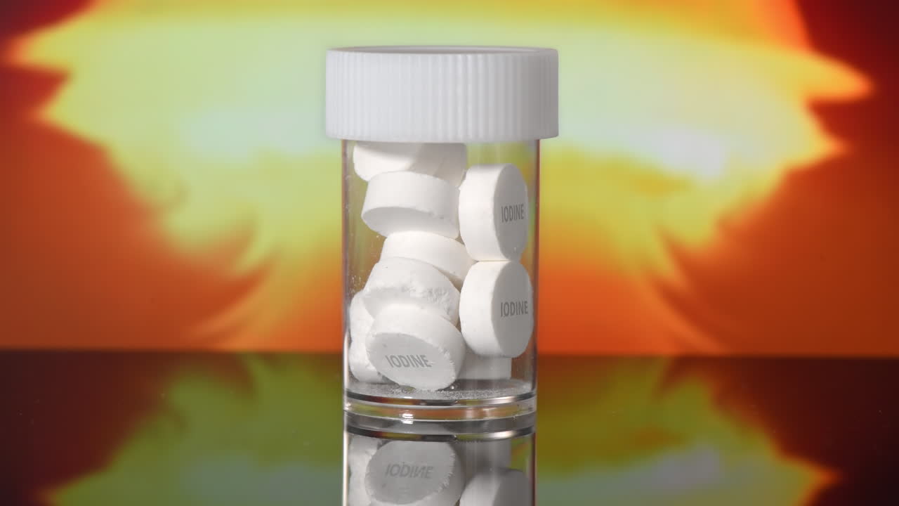 Anti-radiation iodine pills in a jar, nuclear explosion on the background