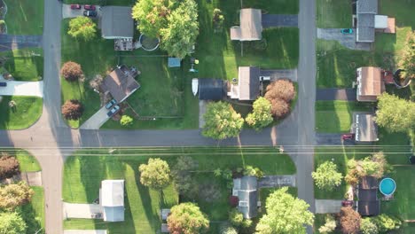 aerial drone bird's eye view over well plaaned town houses with beautiful green gardens during evening time