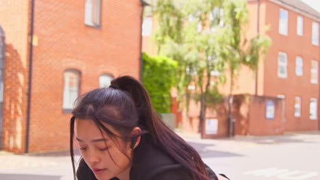 Young-Woman-Exercising-On-Urban-Street-Wearing-Wireless-Earbuds-Checking-Smart-Watch-Before-Run-1