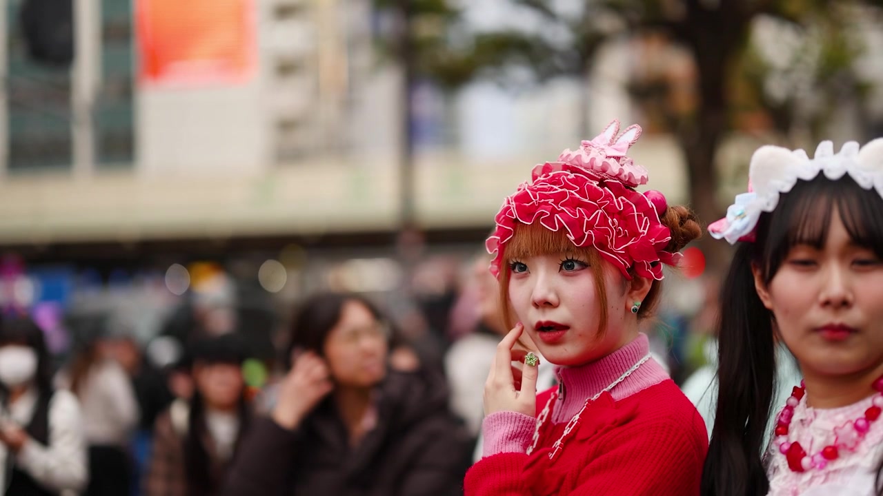 Tokyo, Harajuku'da, canlı pembe decora sokak stilinde giyinmiş genç bir kadın açık havada poz veriyor.