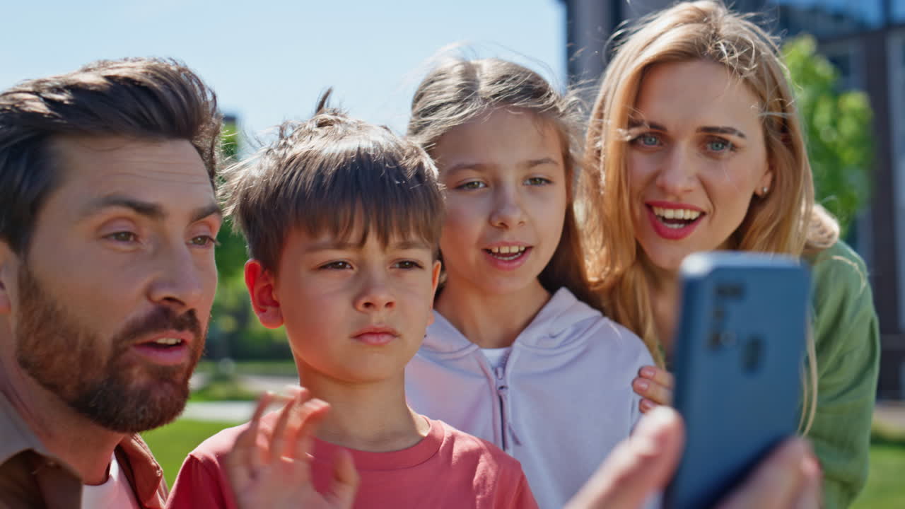 Cheerful relatives videocalling smartphone park portrait. Positive people online