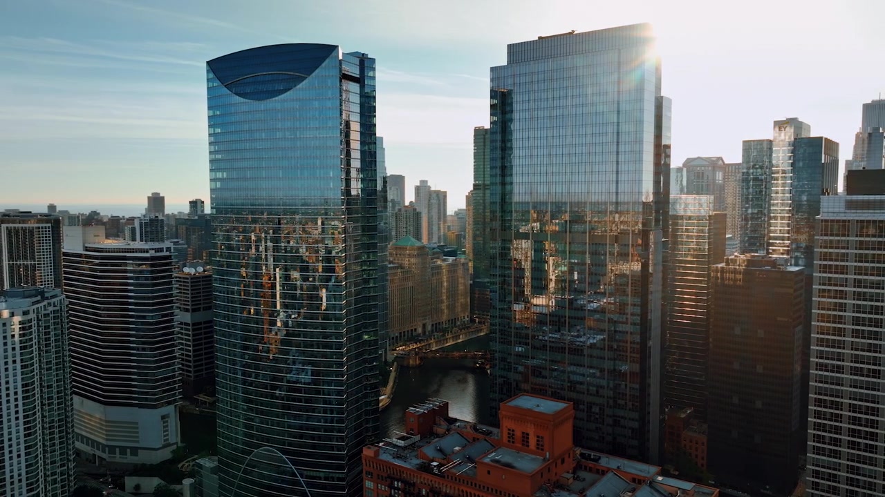 Dois arranha-céus modernos com fachadas espelhadas no cenário do centro de Chicago. Vista aérea de uma metrópole americana ao pôr do sol.