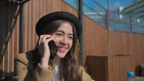 mujer hablando por teléfono en un café al aire libre