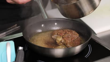 chef searing a piece of meat in a pan