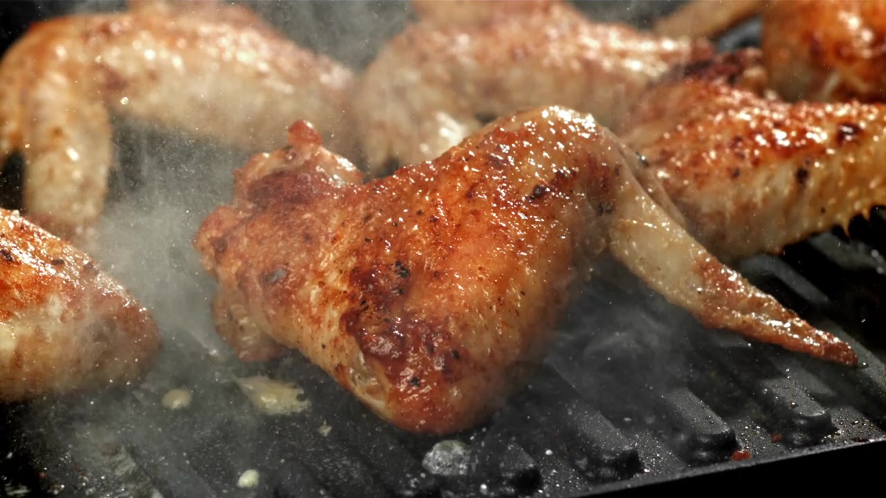 Deliziose alette di pollo che sfrigolano e grigliano su una piastra calda