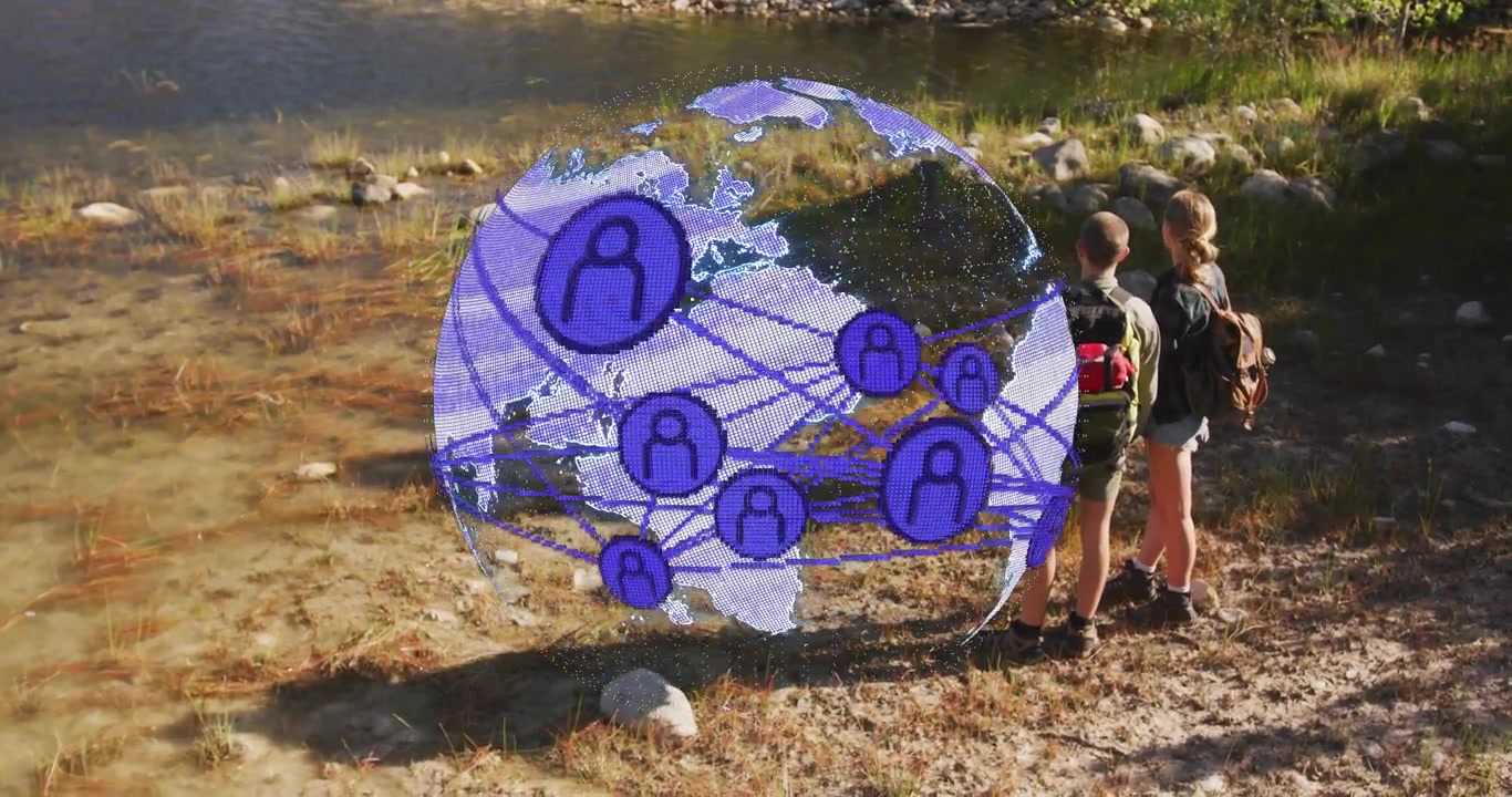 Dos excursionistas a orillas del río activando un globo giratorio que ilustra iconos de red tecnológica y enlaces luminosos.