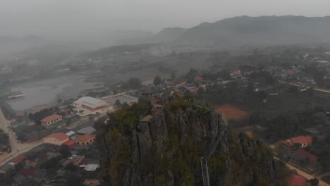 Volando-Alrededor-De-Una-Gran-Roca-En-La-Pequeña-Ciudad-De-Laos,-Aérea