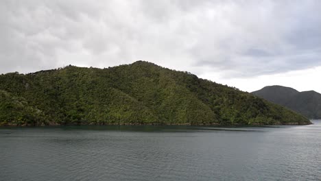 Lush-hills-meet-the-pacific-ocean-in-the-fiords-of-Queen-Charlotte-sounds-underneath-dramatic-clouds