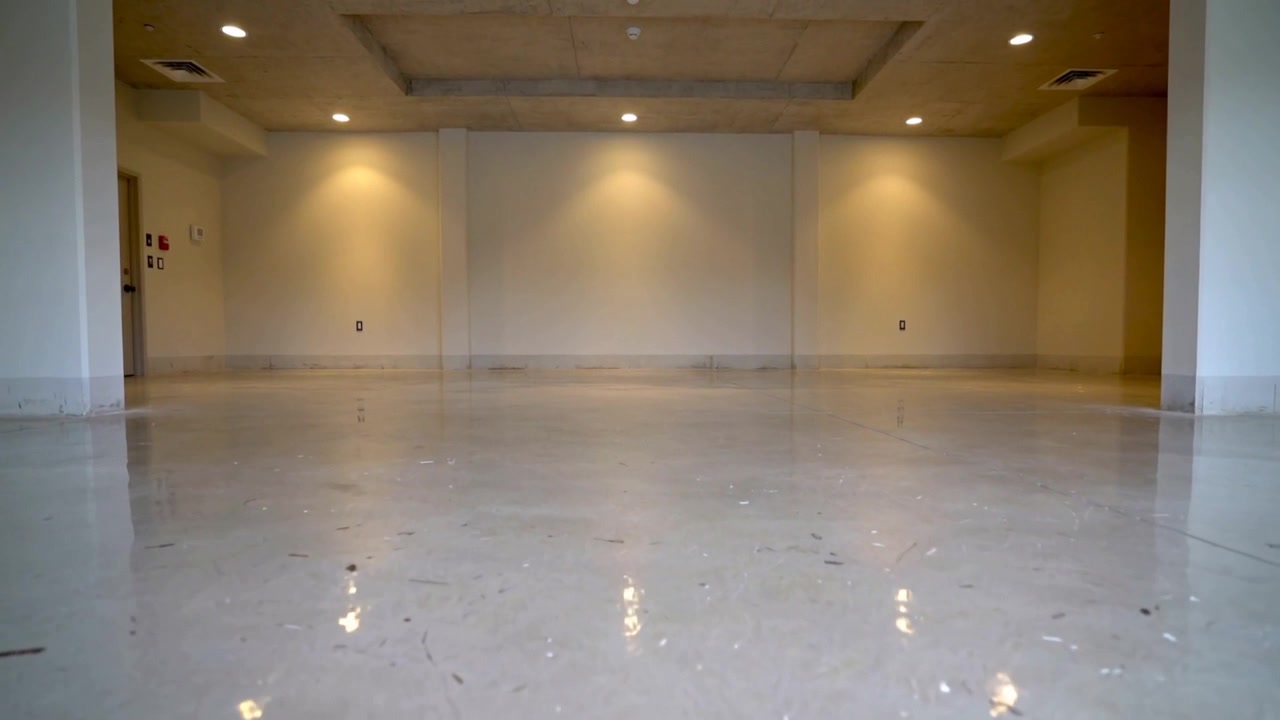Cámara grabando una habitación vacía, documentando el suelo pulido y las luces empotradas para el acondicionamiento.