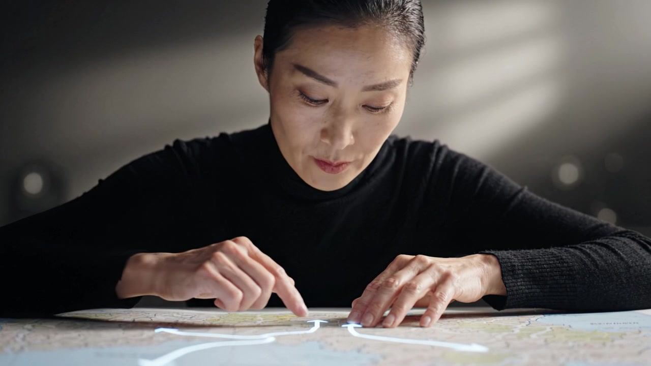 地図を精密に分析する集中した人物が、特定のルートやエリアを強調するためにテクノロジーを駆使し、探求への熱意と決意を示している。