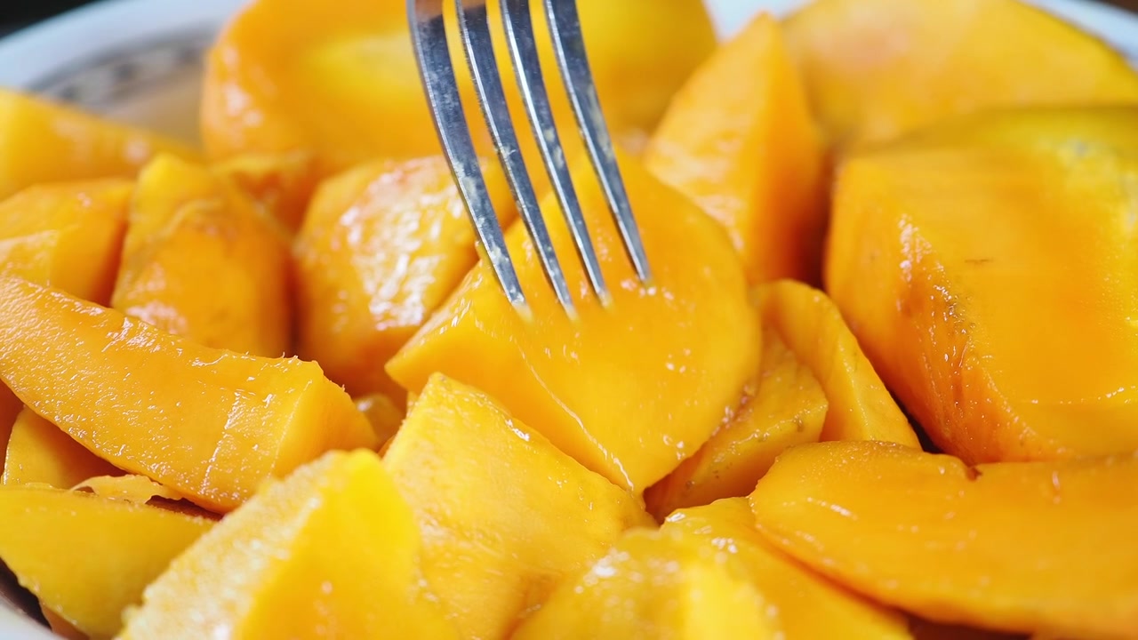 Widelec wbijający się w świeży kawałek dojrzałego mango