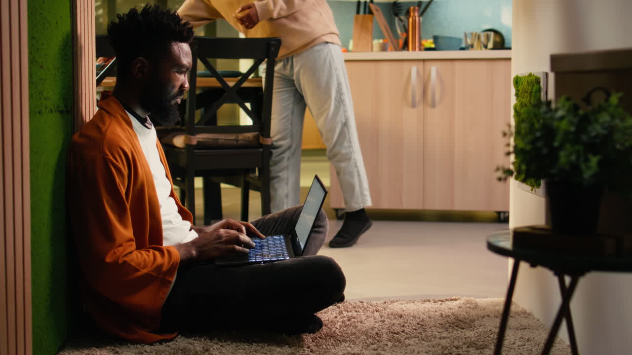 African american person, relaxing with laptop, sitting on the floor at home