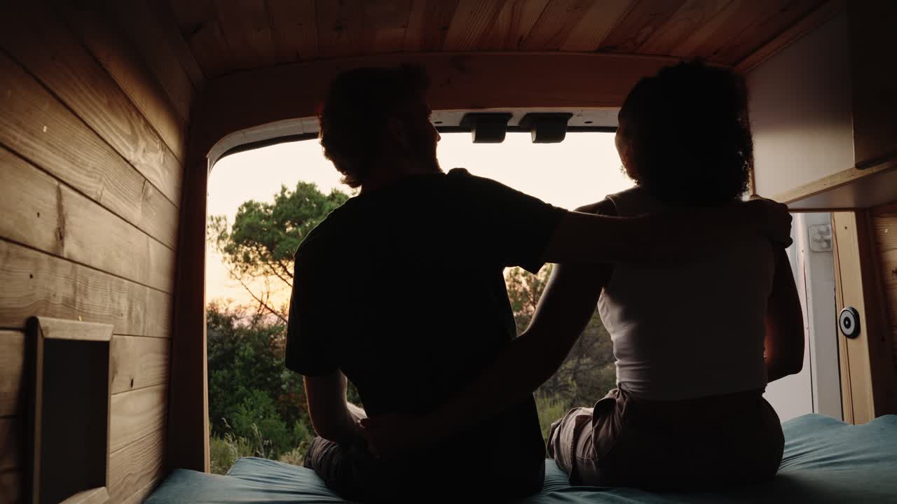 Couple enjoying sunset view from their campervan